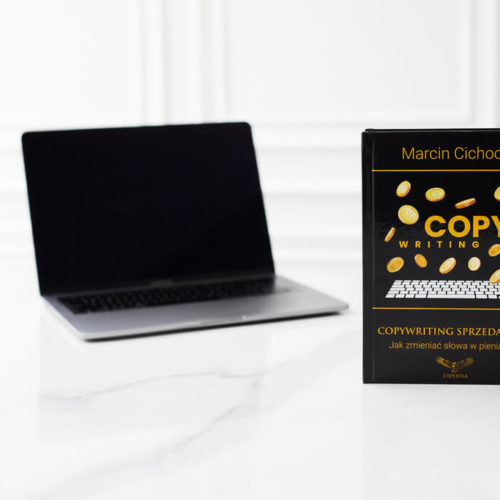 Książka Copywriting sprzedażowy z otwartym laptopem